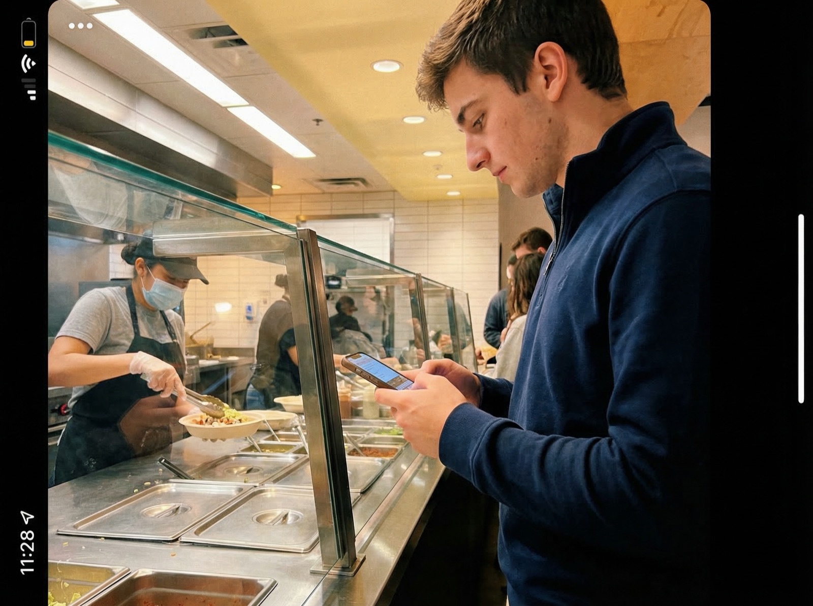 Man checking calorie estimates on his phone while ordering at a fast-casual restaurant